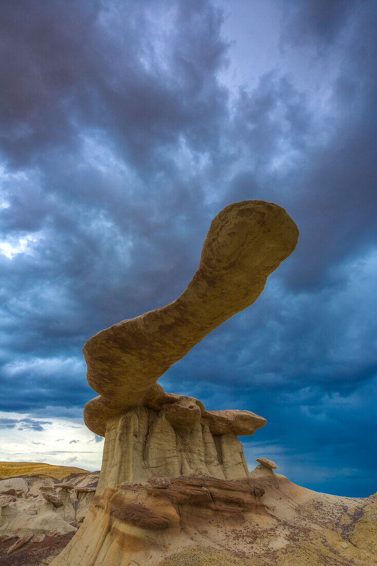 The King of Wings, a very fragile sandstone hoodoo in the badlands of the San Juan Basin in New Mexico, with storm clouds behind.