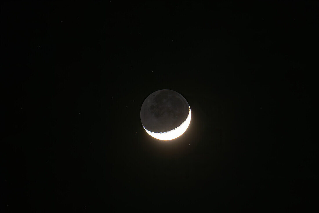 A waxing crescent moon & stars photographed at night with a telephoto lens over the Dominican Republic.