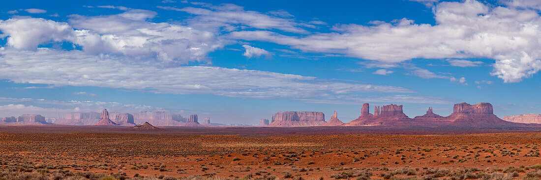 Panoramic view of Monument Valley from the northeast. L-R: Three Sisters at the left end of Mitchell Mesa, East Mitten, Merrick Butte, West Mitten, Gray Whiskers Butte, Mitchell Butte, Sentinal Mesa, Big Indian Chief, Castle Butte, Bear & Rabbit, Stagecoach, King on the Throne, Brigham's Tomb, & Eagle Mesa at far right behind. The border between Arizona & Utah is between Mitchell Butte & Sentinal Mesa, almost in the very center of the image, wtih Utah at right.