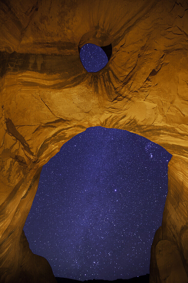 The Milky Way through the Big Hogan Arch at night in the Monument Valley Navajo Tribal Park in Arizona.