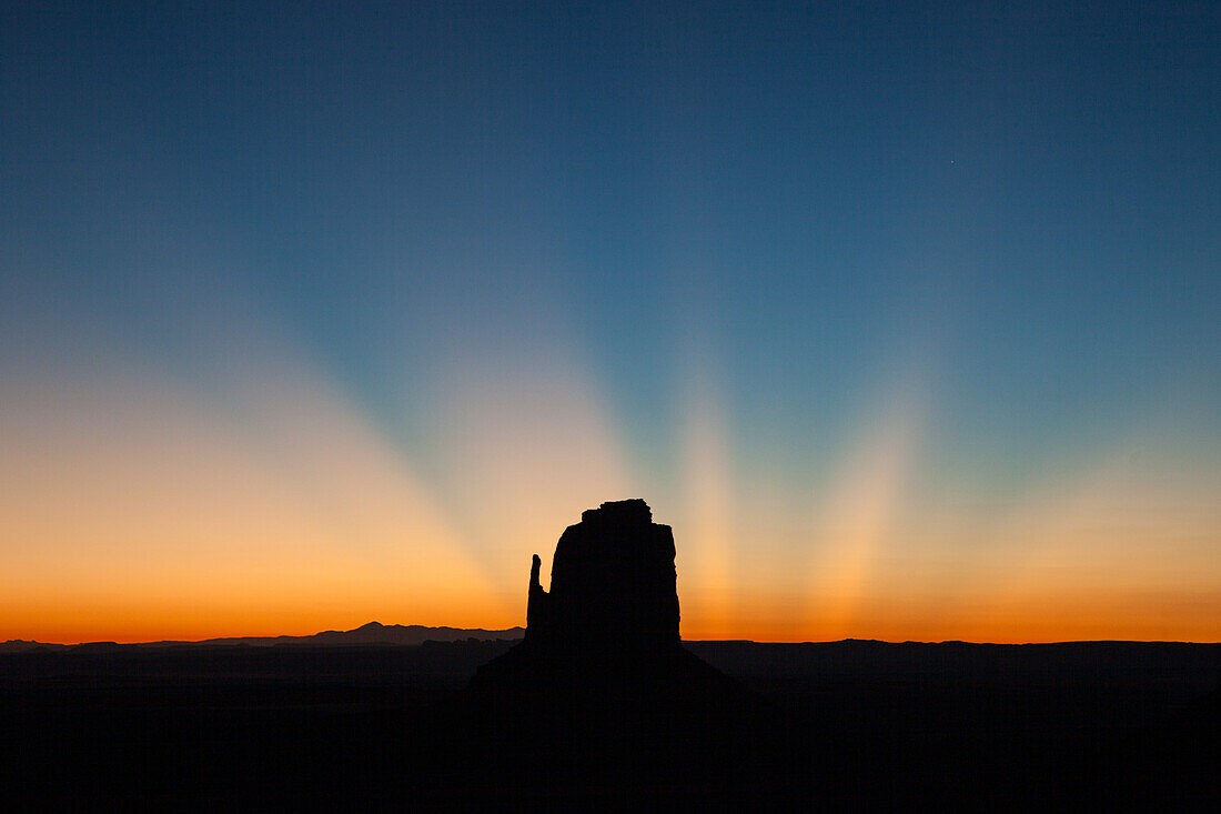 Dämmrige Sonnenstrahlen über dem East Mitten vor der Morgendämmerung im Monument Valley Navajo Tribal Park in Arizona