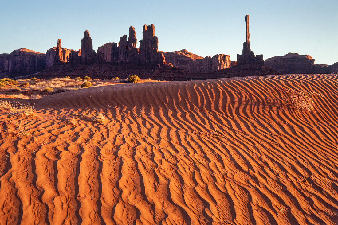 The Totem Pole & Yei Bi Chei with rippled sand dunes in the Monument Valley Navajo Tribal Park in Arizona.