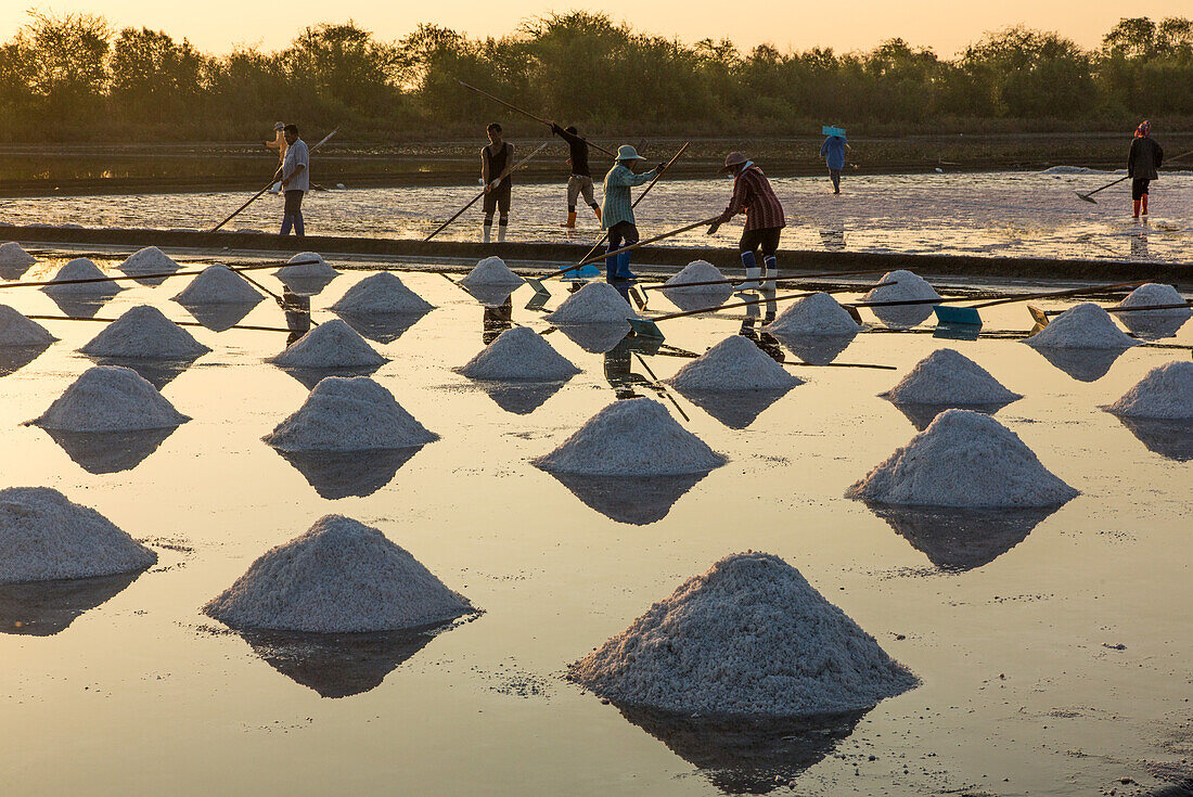 Arbeiter, die auf einer Salzfarm in Samut Sakhon, Thailand, Salz nach traditionellen, seit Jahrtausenden angewandten Methoden gewinnen