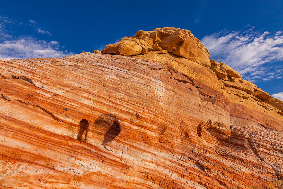 A small piano-leg arch in a colorful eroded Aztec sandstone formation in Valley of Fire State Park in Nevada.