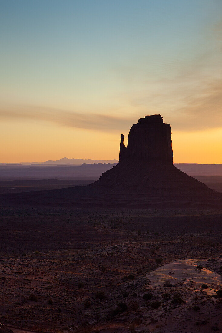 Colorful sunrise sky behind the East Mitten Butte in the Monument Valley Navajo Tribal Park in Arizona.