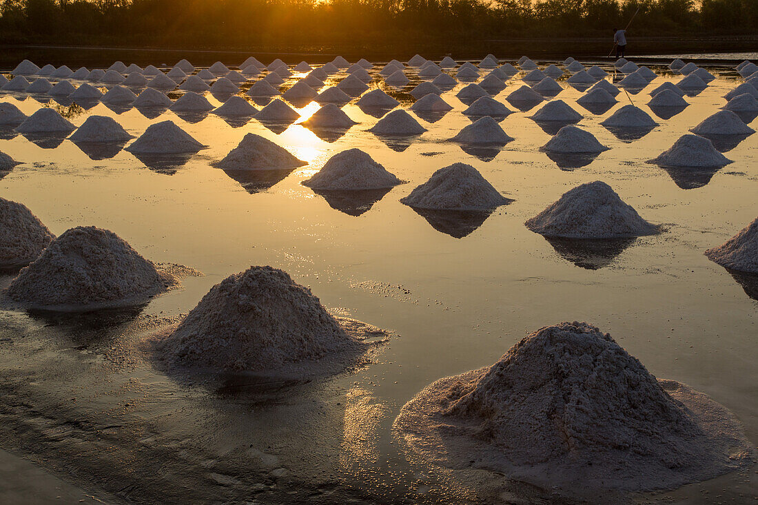 Salzhaufen bilden geometrische Muster auf der Salzpfanne in einer traditionellen Verdunstungssalzfarm in Samut Sakhon, Thailand