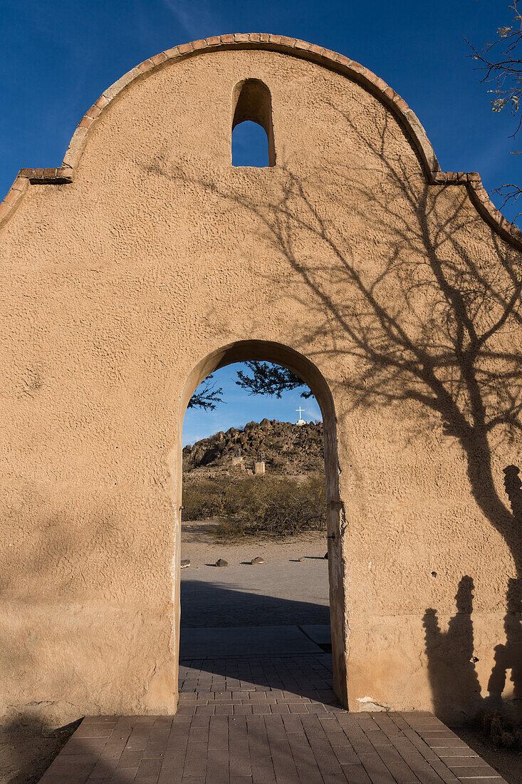 Ein gewölbter Durchgang durch die Schutzmauer der Mission San Xavier del Bac umrahmt den Grotto Hill, Tucson Arizona