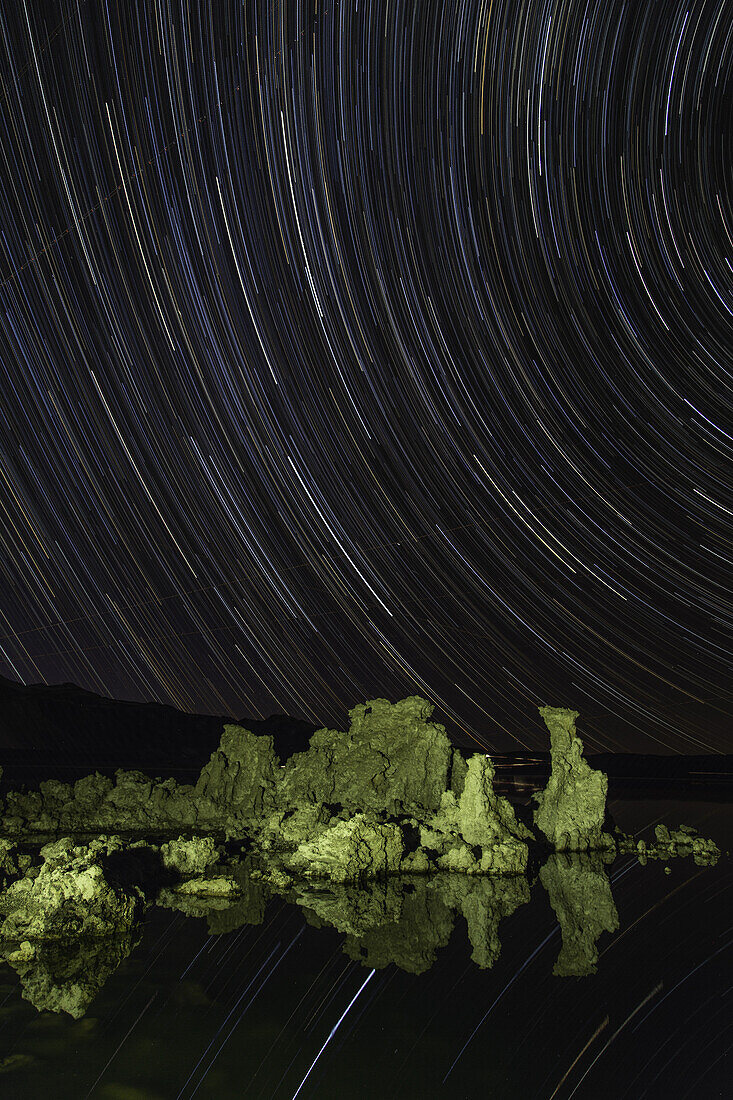 Star trails over tufa formations in Mono Lake in California with trails reflected in the lake.