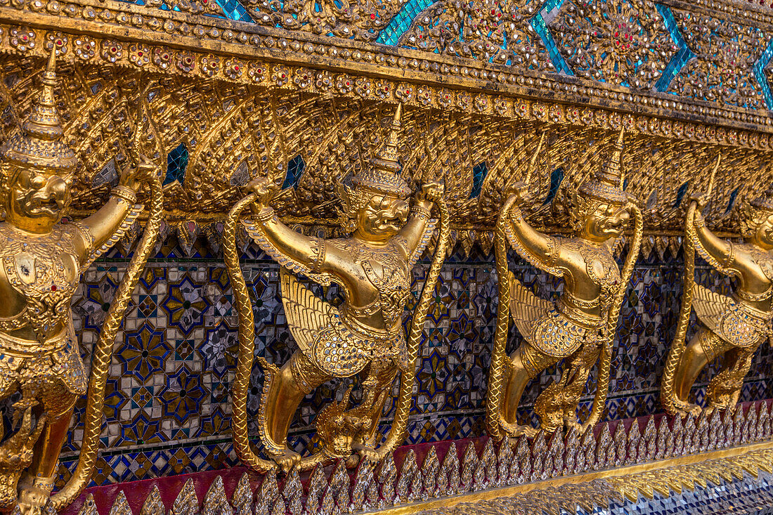 Goldene Statuen von Garuda und Naga bewachen den Tempel des Smaragdbuddhas im Grand Palace in Bangkok, Thailand