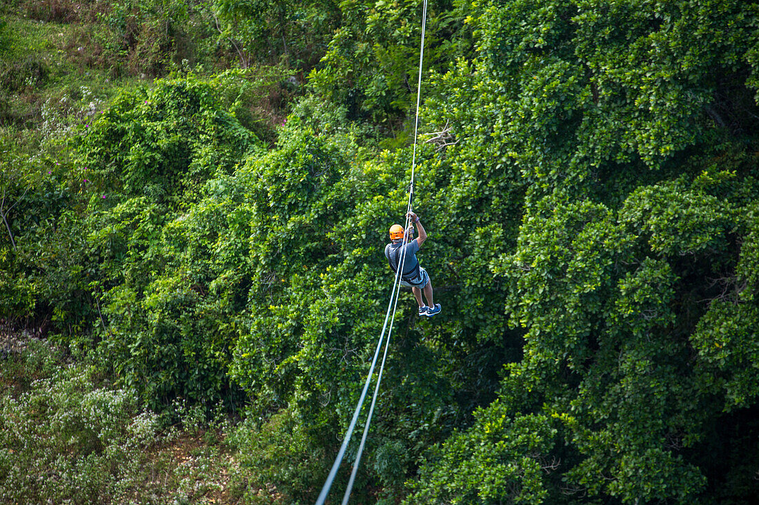 Ein Mann beim Ziplining über dem Regenwald bei Sosua in der Dominikanischen Republik