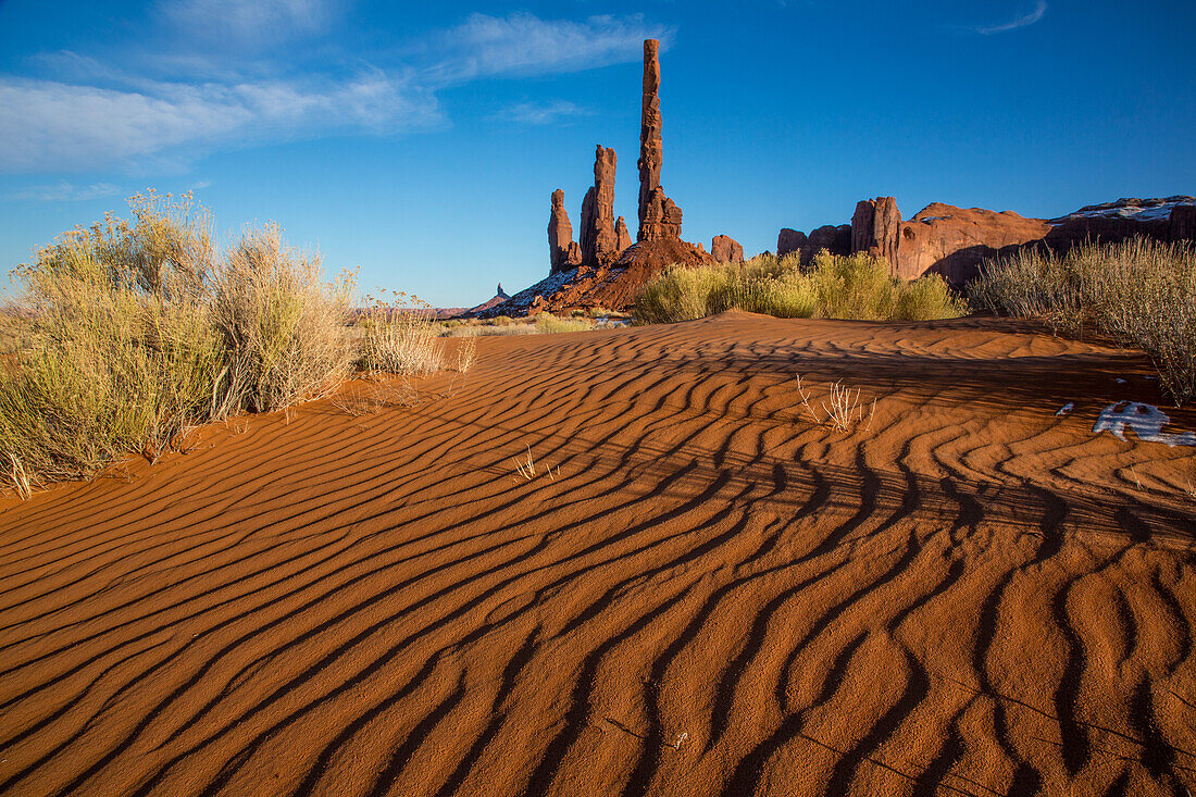The Totem Pole, Yei Bi Chei and Rooster Rock with rippled sand in the Monument Valley Navajo Tribal Park in Arizona.