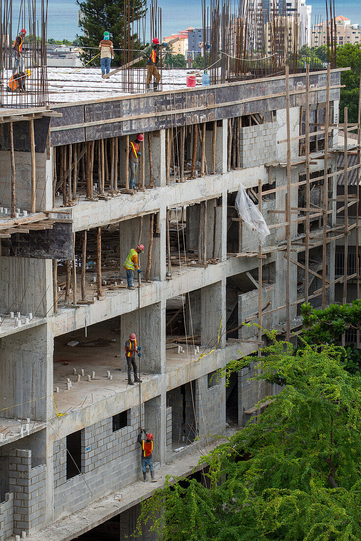 Bauarbeiter arbeiten an einem Wohnhaus im Zentrum von Santo Domingo, Dominikanische Republik. Sie transportieren Bewehrungseisen mit der Hand