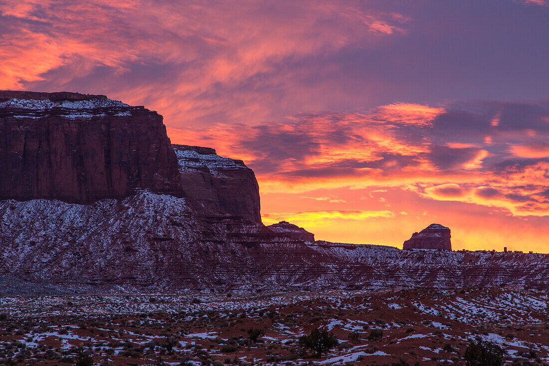 Farbenfroher Sonnenuntergang über Mitchell Mesa und dem Grey Whiskers Butte im Monument Valley Navajo Tribal Park in Arizona