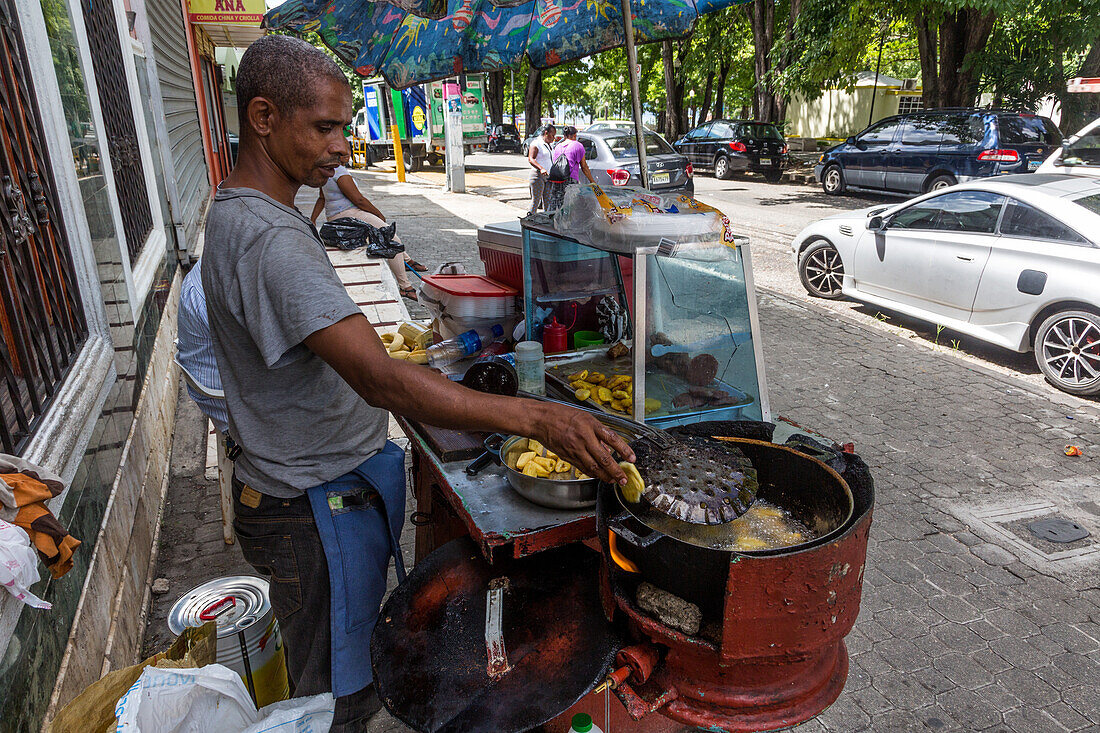 Ein dominikanischer Mann brät Toaststeine in einem mobilen Küchenstand auf der Straße in Santo Domingo, Dominikanische Republik