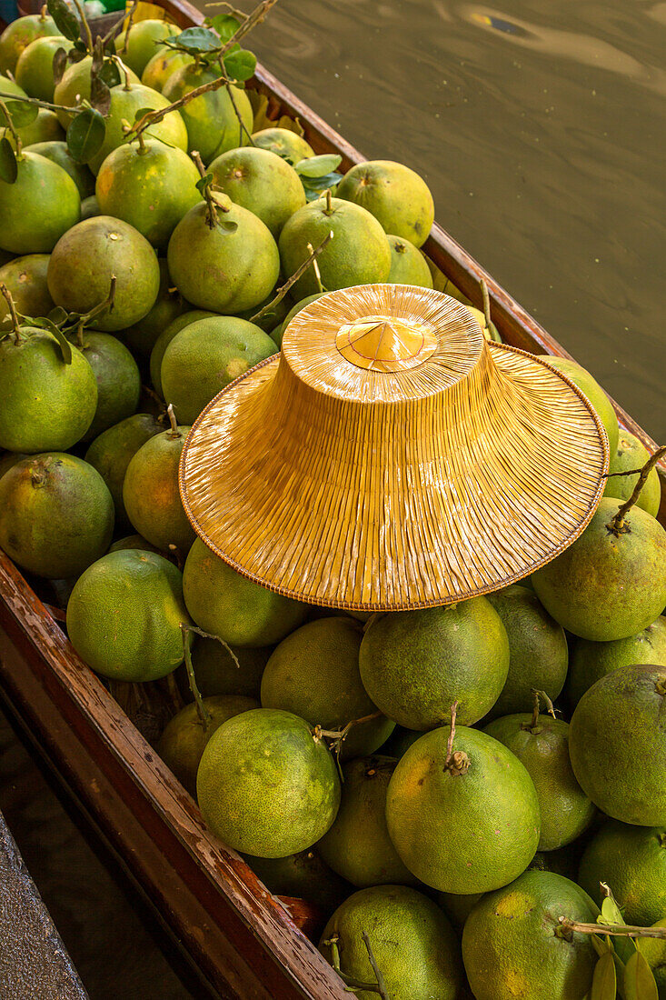 Ein traditioneller thailändischer Hut und Sapodilla-Früchte, die auf einem Boot auf dem schwimmenden Markt von Damnoen Saduak in Thailand verkauft werden