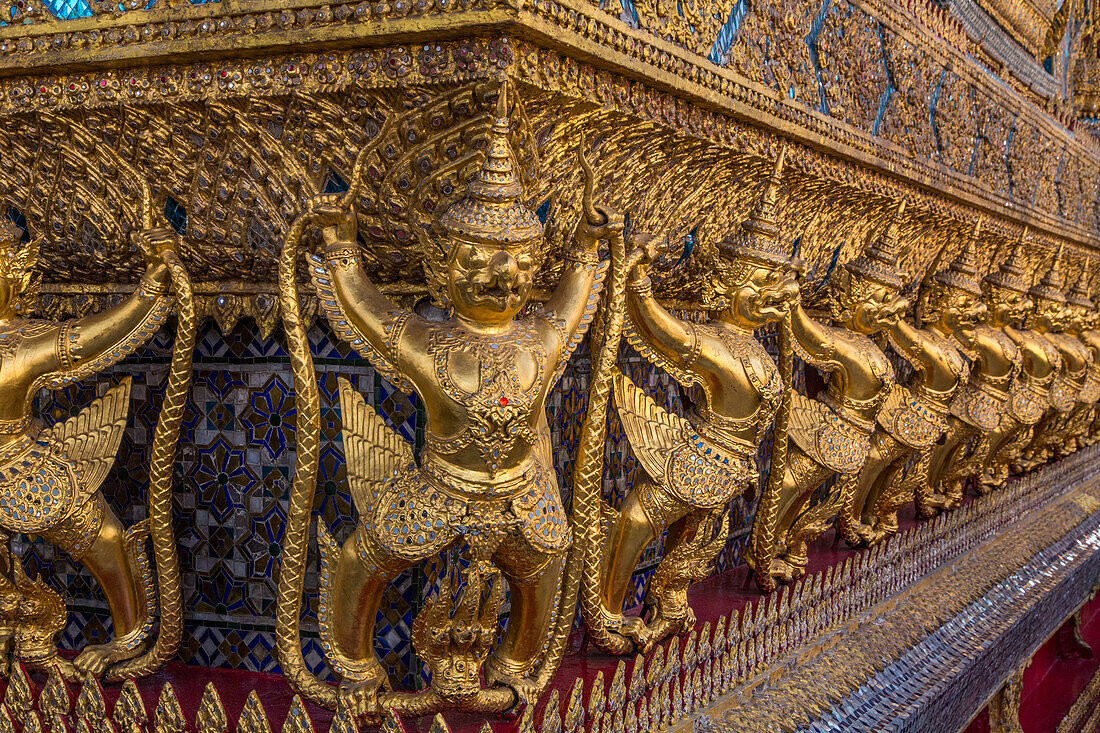 Golden statues of Garuda vs. the naga guards the Temple of the Emerald Buddha in the Grand Palace complex in Bangkok, Thailand.