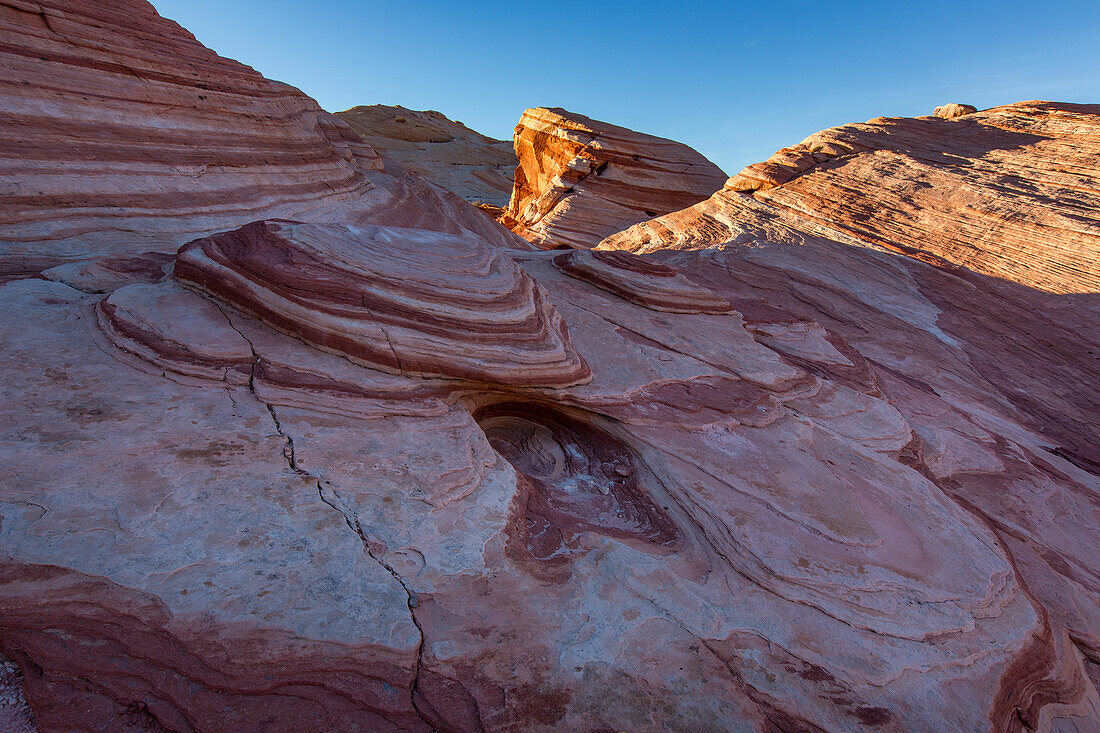 Red & white striped Aztec sandstone formations at sunset in Valley of Fire State Park in Nevada.
