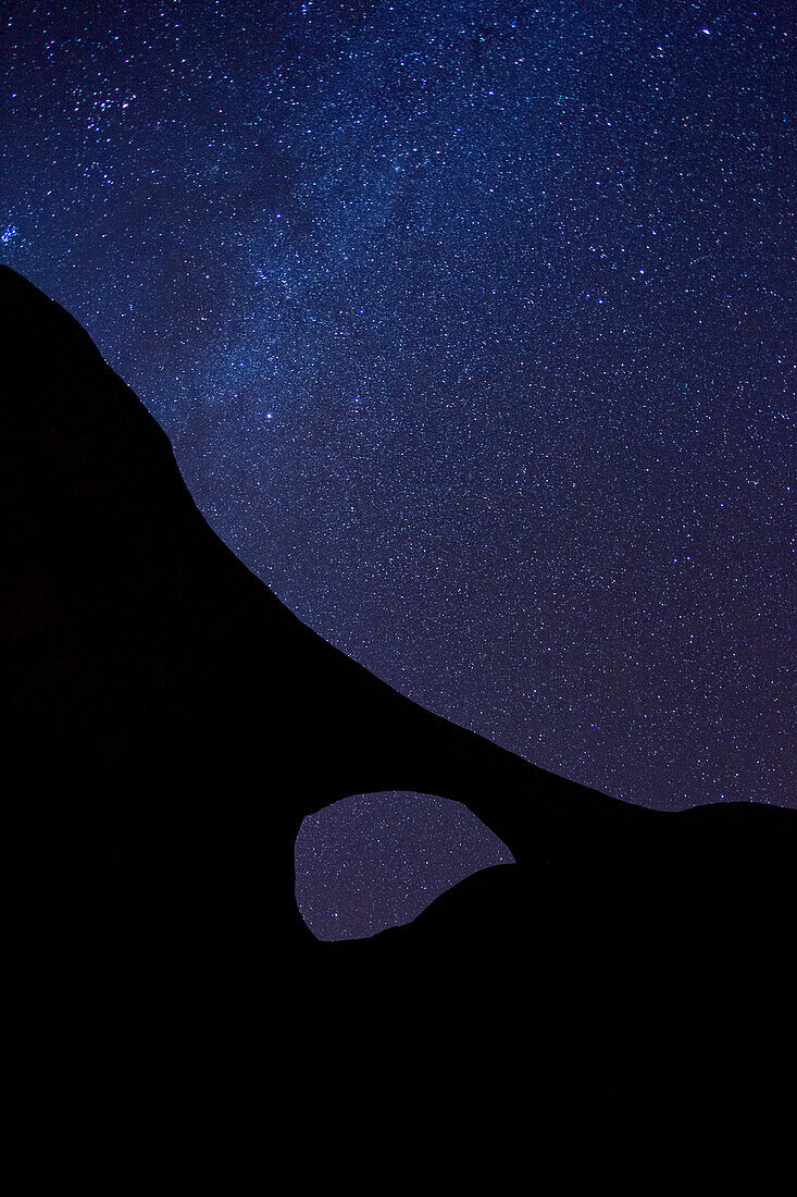 The Milky Way over Moccasin Arch at night in the Monument Valley Navajo Tribal Park in Arizona.