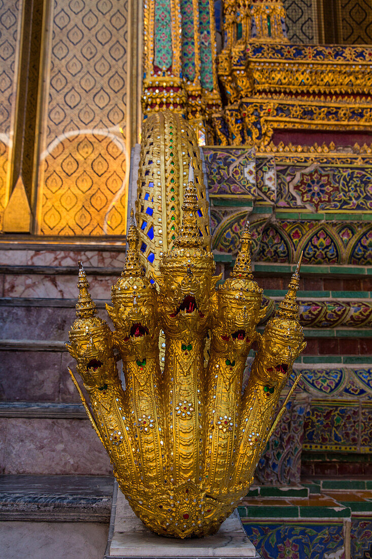 A golden five-head naga, or water deity, on the steps of Phra Mondhop in the Grand Palace complex in Bangkok, Thailand.