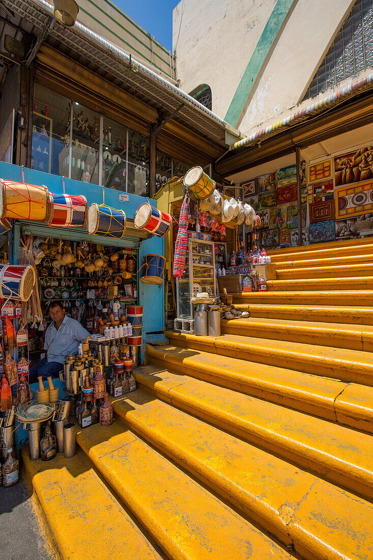 Die berühmte gelbe Treppe, die zum Mercado Modelo in Santo Domingo, Dominikanische Republik, hinaufführt. Ein Ladenbesitzer verkauft Trommeln