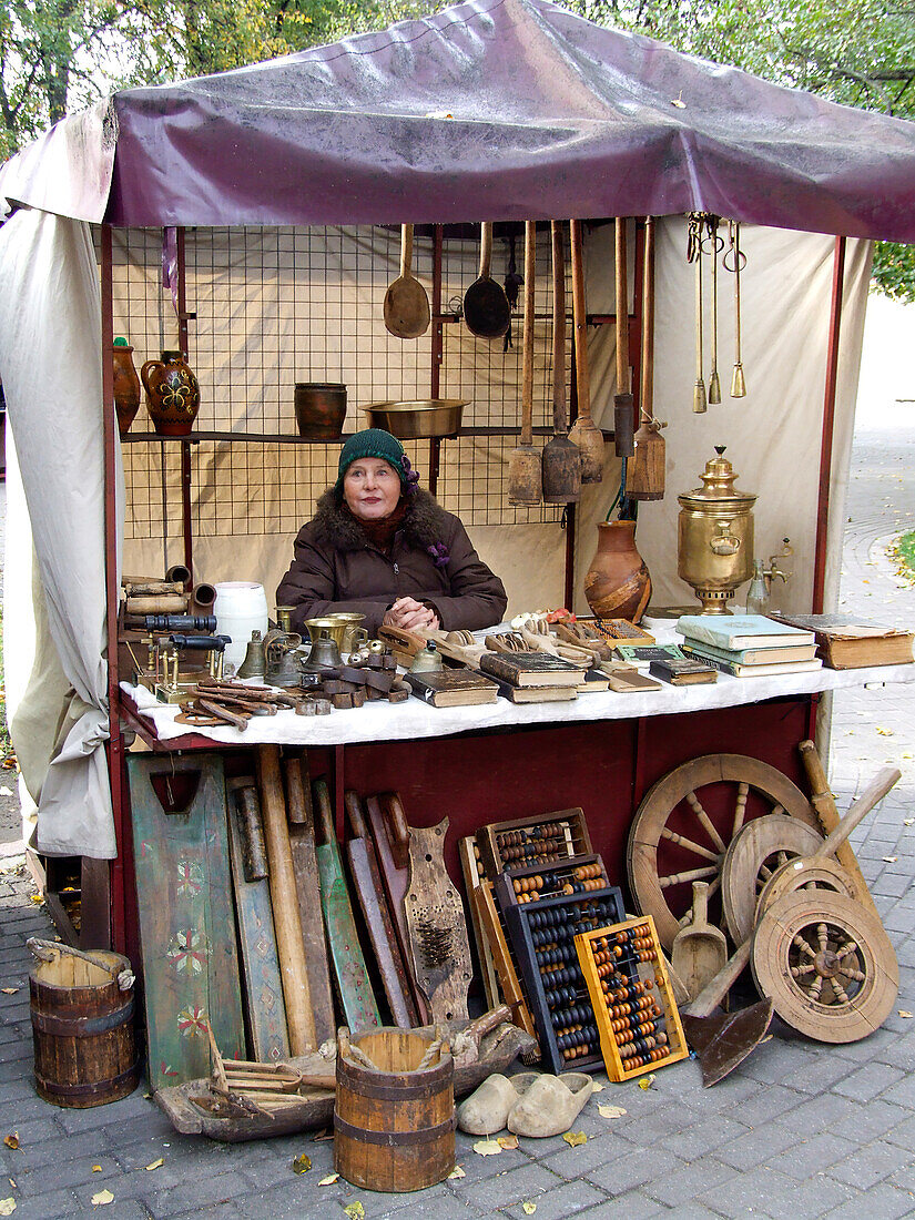 A woman sells antiques in a street market in the Old Town of Vilnius, Lithuania. A UNESCO World Heritage Site.