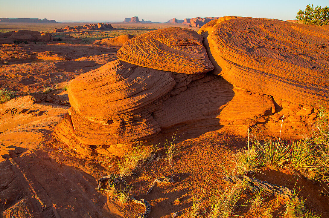 Eroded sandstone in Mystery Valley in the Monument Valley Navajo Tribal Park in Arizona. The Utah monuments are behind.