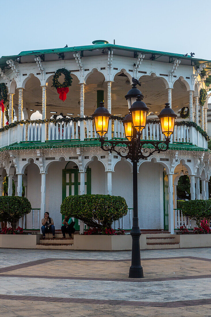 Straßenlaternen und ein weihnachtlich geschmückter viktorianischer Pavillon oder Musikpavillon auf dem Unabhängigkeitsplatz in Puerto Plata, Dominikanische Republik