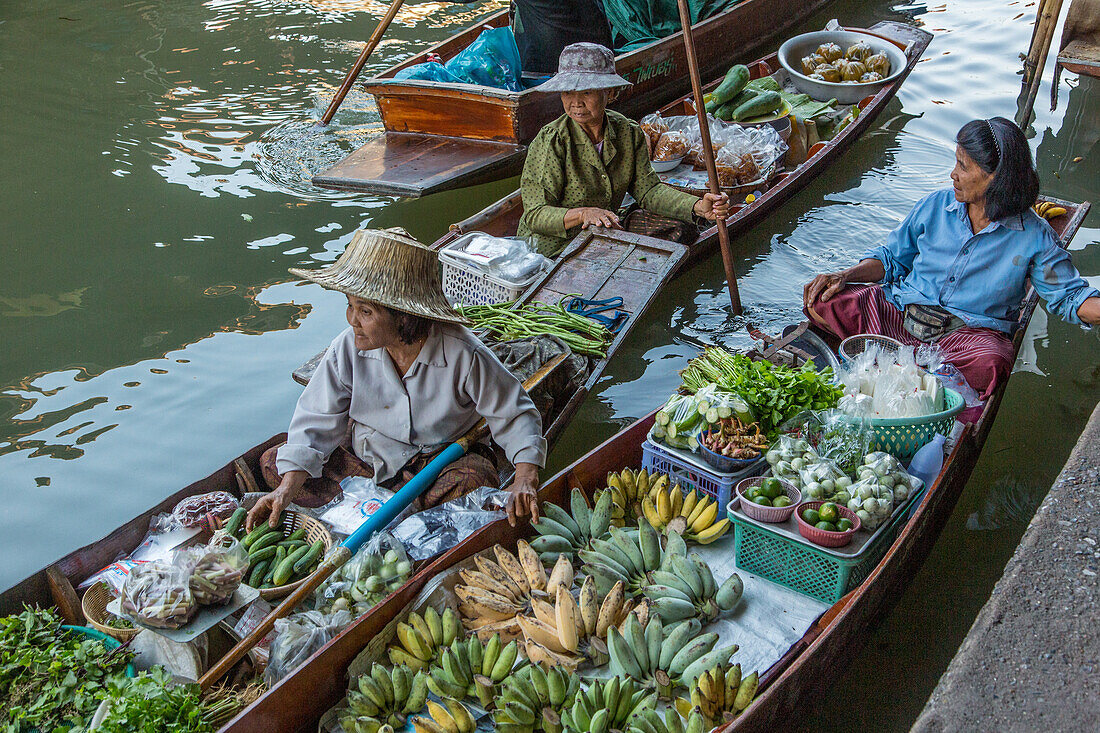 Social interaction between Thai vendors on their boats in the Damnoen Saduak Floating Market in Thailand.