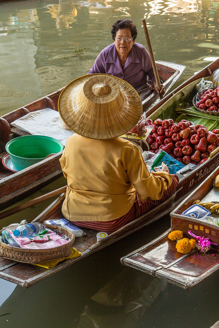 Social interaction between Thai vendors on their boats in the Damnoen Saduak Floating Market in Thailand.