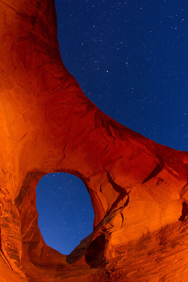 Stars through the Ear of the Wind Arch at night in the Monument Valley Navajo Tribal Park in Arizona.
