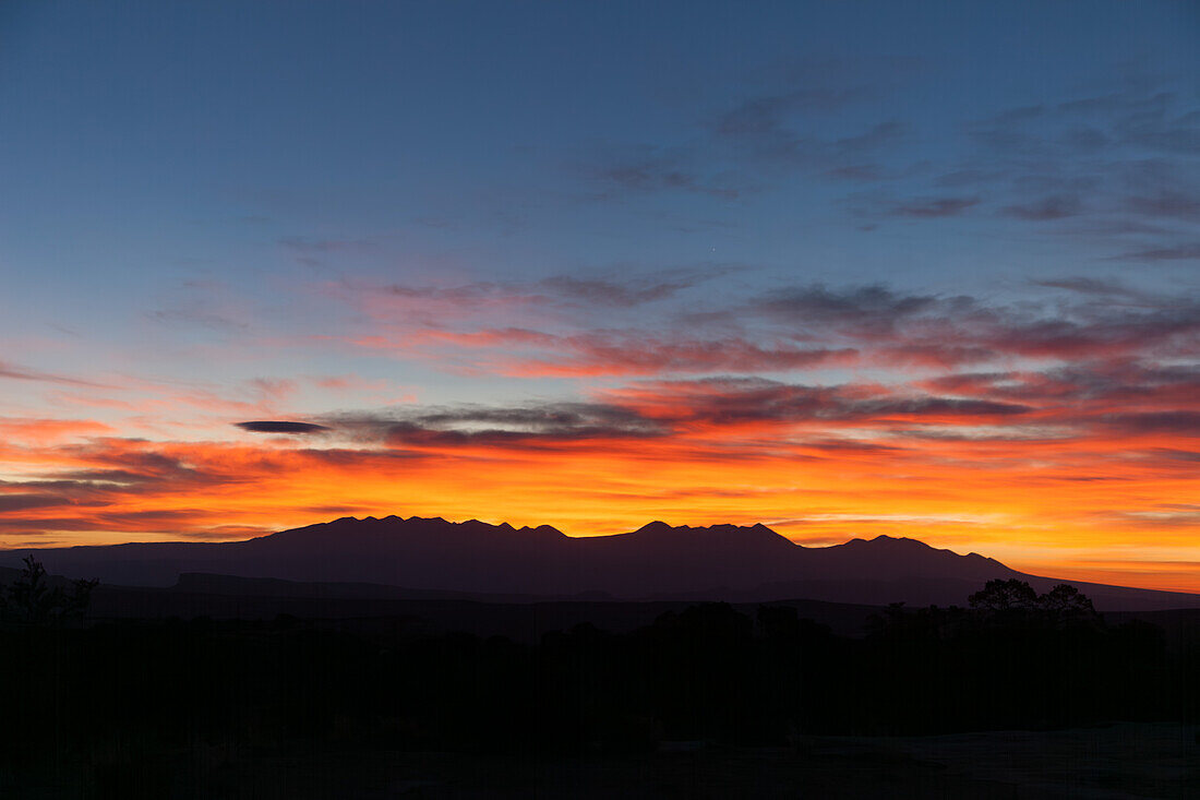Farbenfrohe Wolken bei Sonnenaufgang über den La Sal Mountains und der Canyon-Landschaft bei Moab, Utah