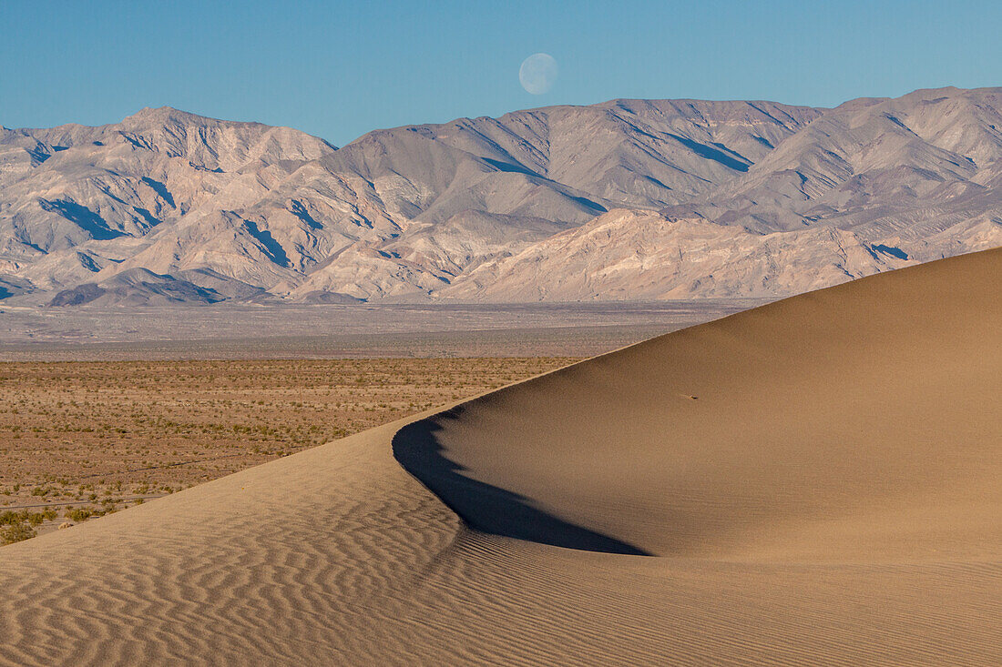 Setting moon over the Mesquite Flat sand dunes & Panamint Mountains in Death Valley National Park in the Mojave Desert, California.