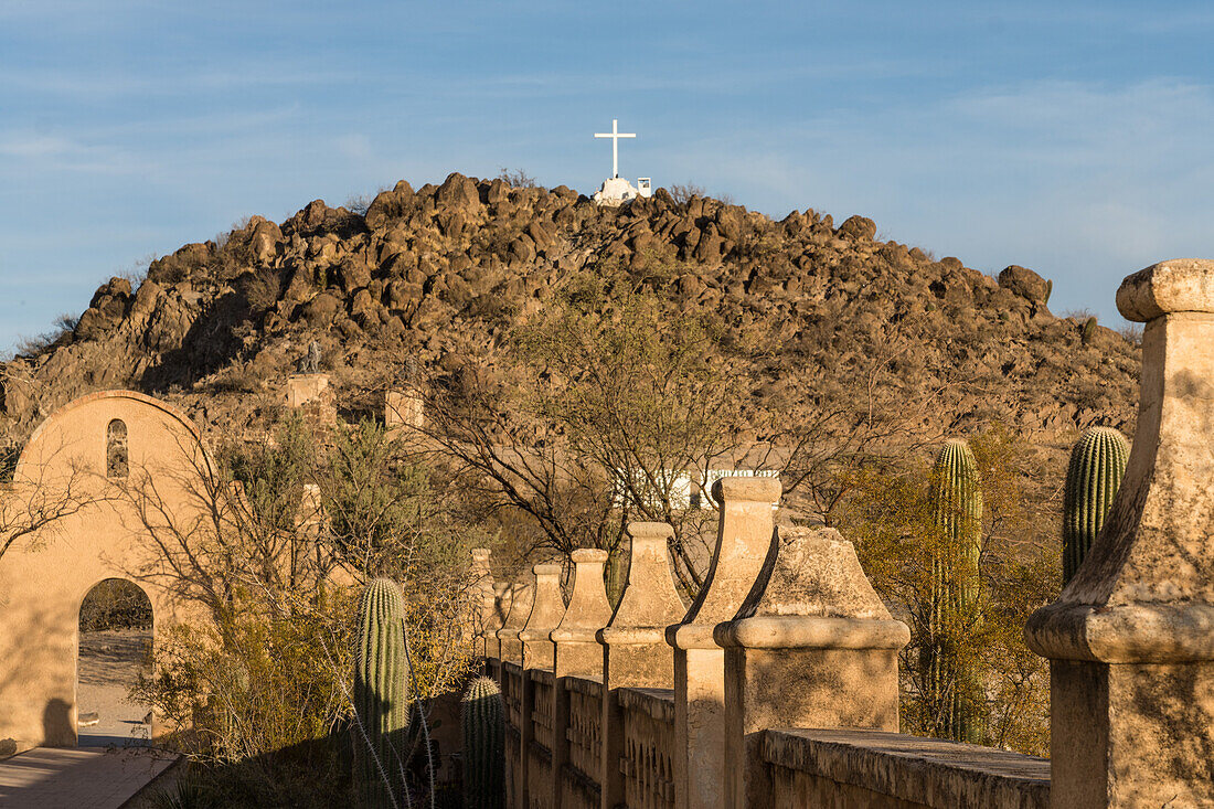 Arched doorway through the protective wall around the Mission San Xavier del Bac, Tucson Arizona. The Grotto Hill with its white cross is behind.