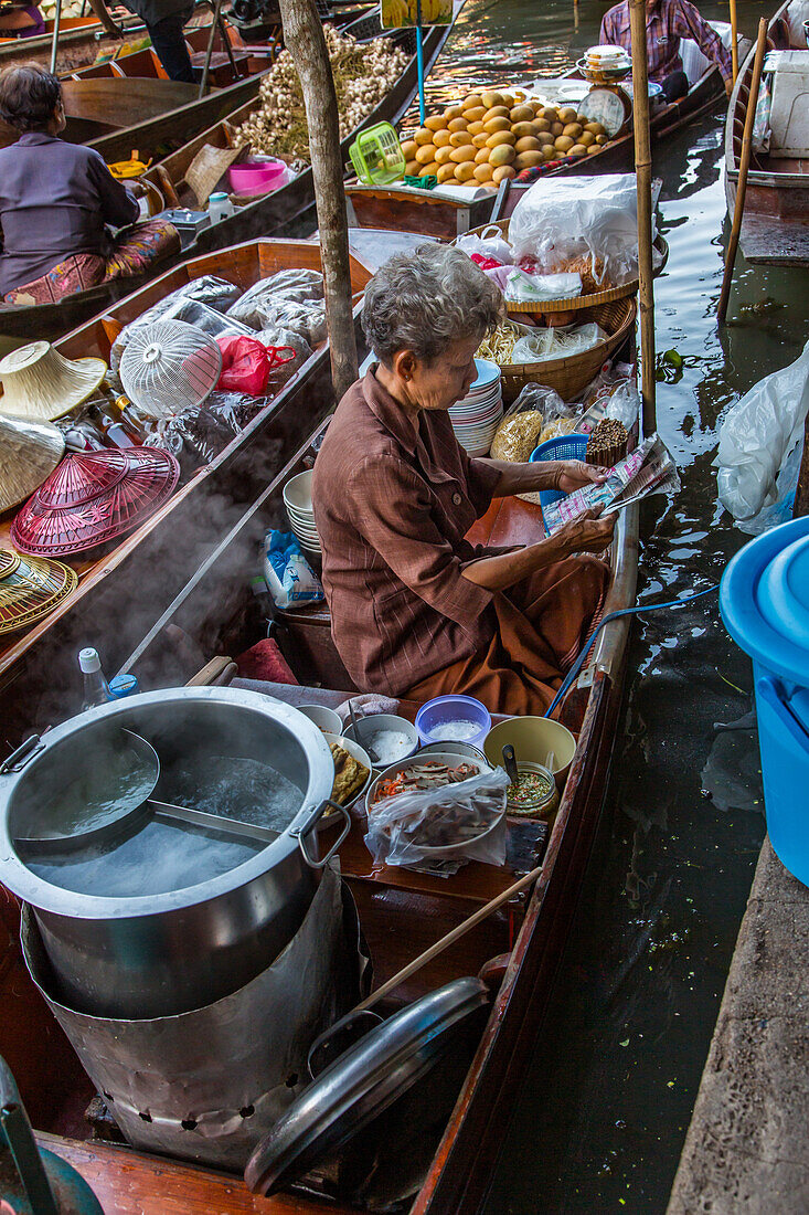 Eine Thailänderin auf ihrem schwimmenden Küchenboot auf dem schwimmenden Markt von Damnoen Saduak in Thailand