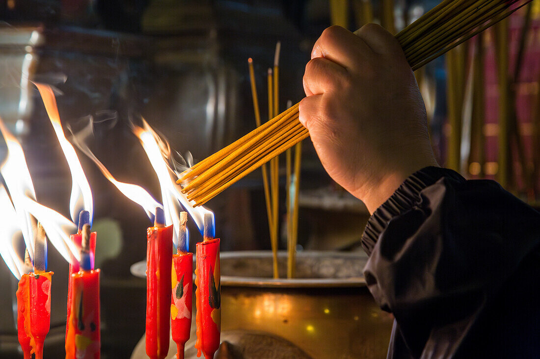 A worshipper lights joss sticks or incense in the Buddhist Man Mo Temple in Hong Kong, China.