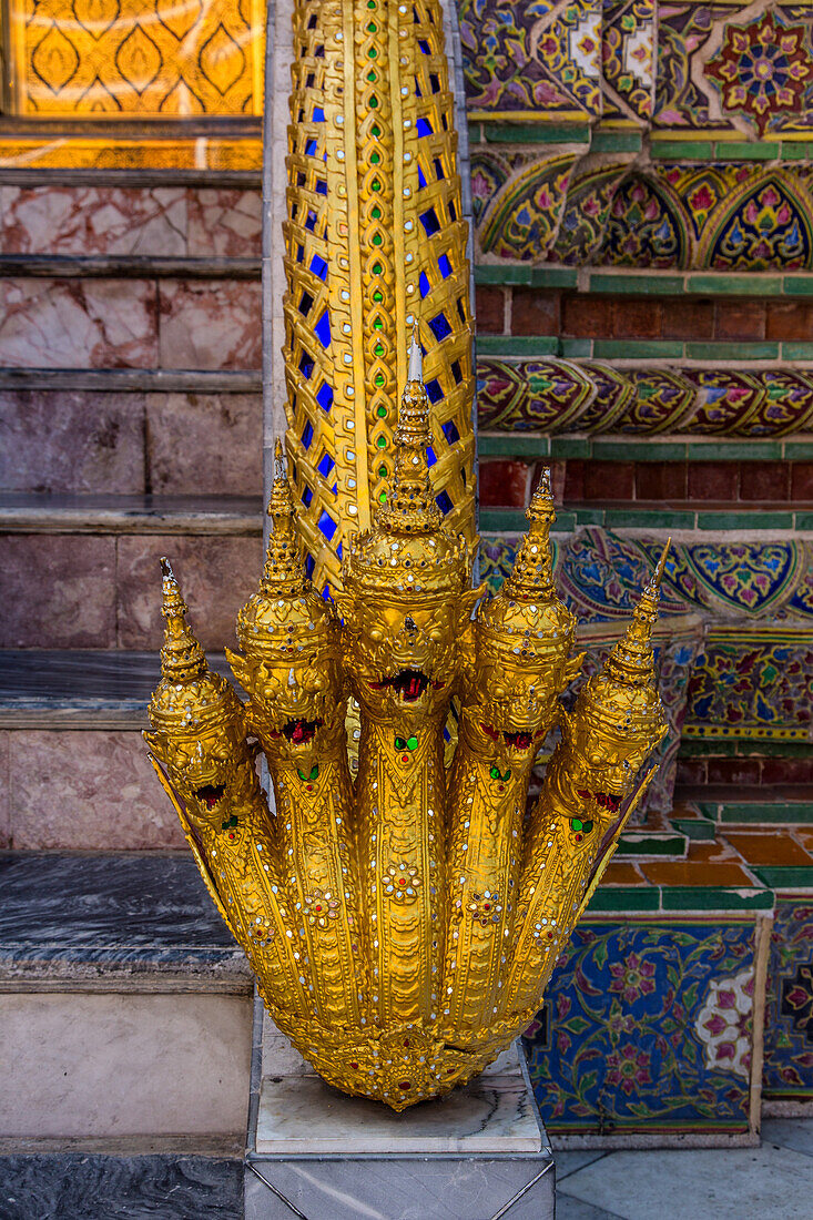 A golden five-head naga, or water deity, on the steps of Phra Mondhop in the Grand Palace complex in Bangkok, Thailand.