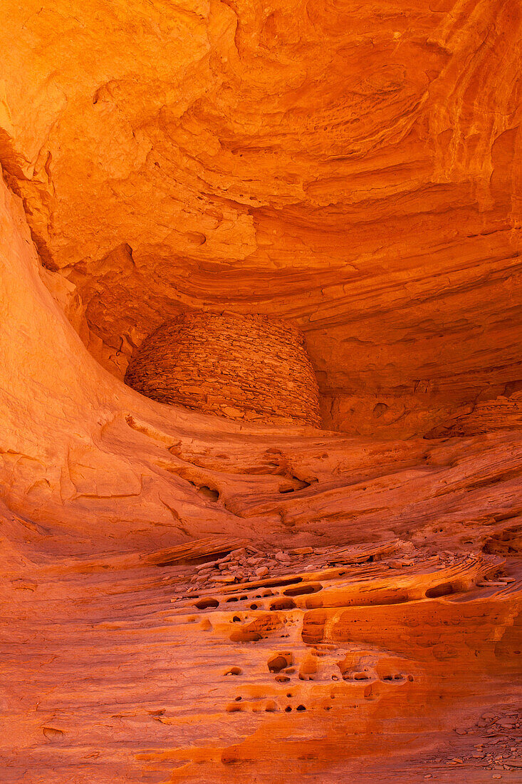 An Ancestral Puebloan ruin inside Honeymoon Arch in Mystery Valley in the Monument Valley Navajo Tribal Park in Arizona. In front is tafoni or rock lace erosion in the sandstone.