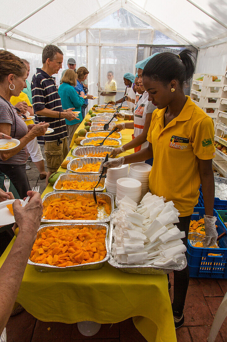 Touristen probieren auf der Mango-Expo in Bani, Dominikanische Republik, am Mango-Verkostungsstand verschiedene Sorten von Mangos