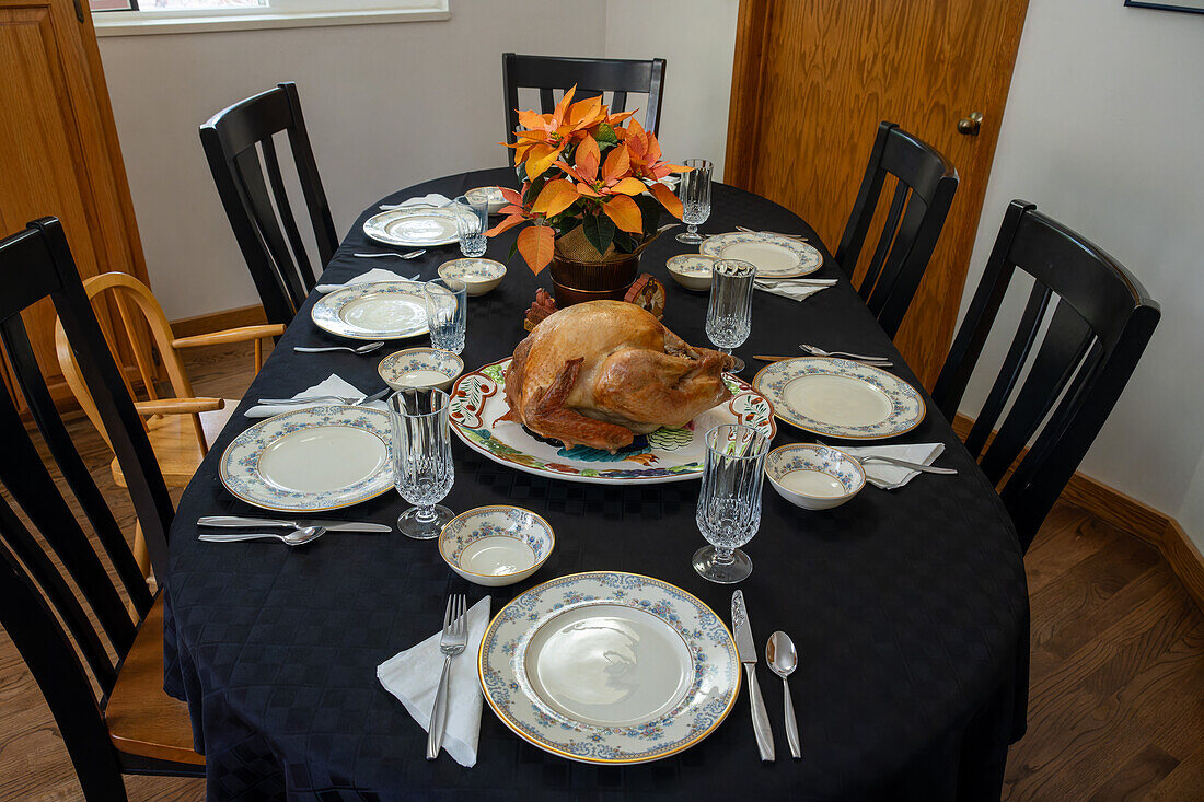 Table setting for a Thanksgiving holiday dinner with a roasted turkey, English fine china & crystal stemware in Utah.