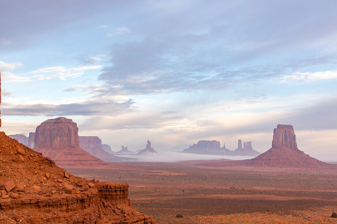Foggy morning North Window view of the Utah monuments in the Monument Valley Navajo Tribal Park in Arizona. L-R: Elephant Butte (foreground), Merrick Butte with Sentinal Mesa behind, Setting Hen, Big Indian Chief, Brigham's Tomb, King on the Throne, Castle Butte, Bear and Rabbit, Stagecoach, East Mitten Butte.