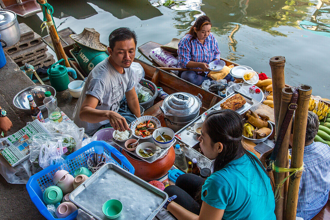 Thai people eating from a floating kitchen boat in the Damnoen Saduak Floating Market in Thailand.