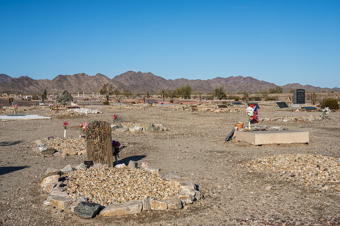 Gräber auf dem Friedhof in Quartzsite, Arizona, mit den Dome Rock Mountains im Hintergrund