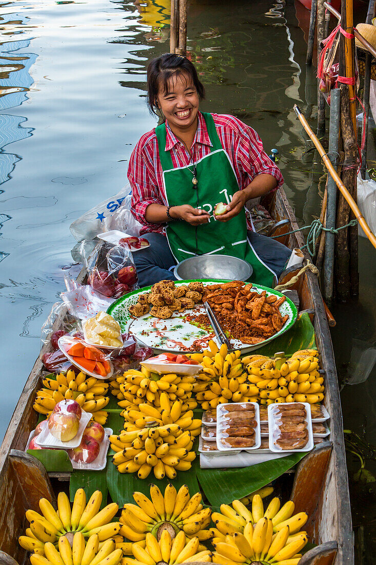 Eine thailändische Frau bereitet auf ihrem Boot auf dem schwimmenden Markt von Damnoen Saduak in Thailand Essen zu