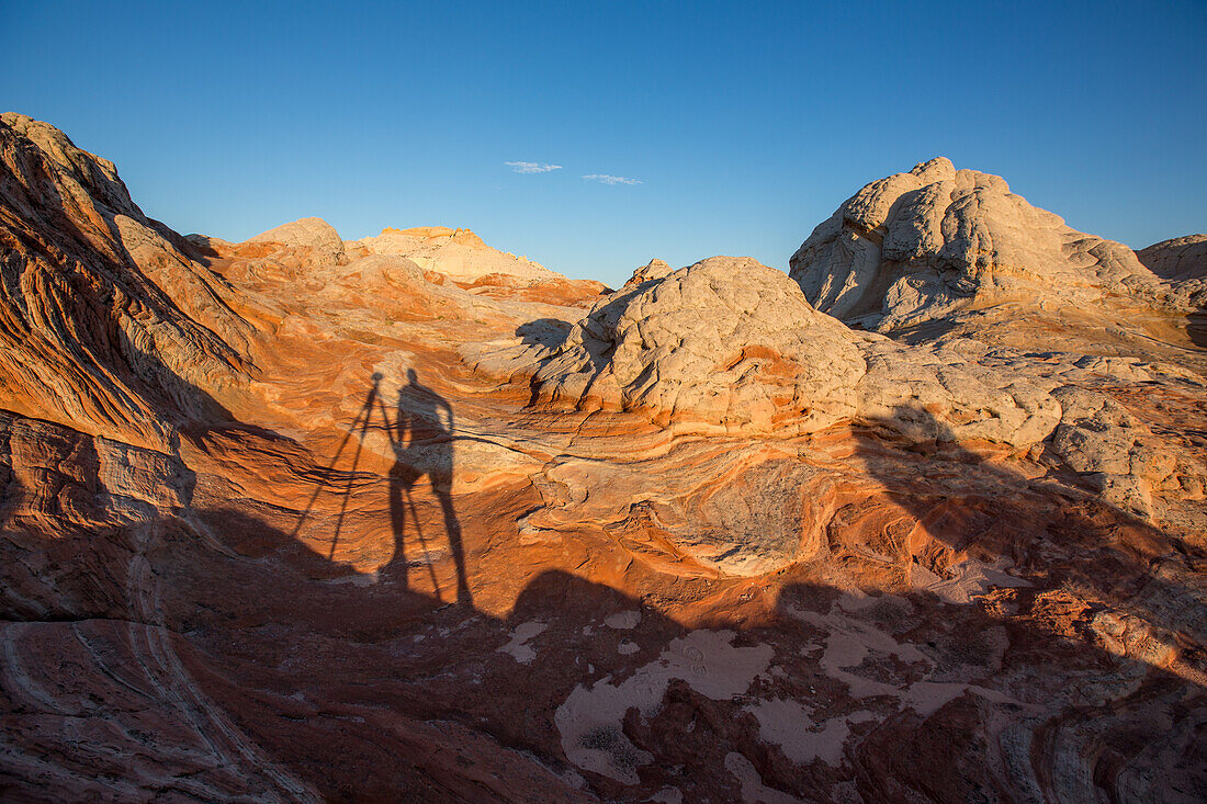 Der Schatten eines Landschaftsfotografen mit Kamera und Stativ beim Fotografieren der White Pocket Recreation Area, Vermilion Cliffs National Monument, Arizona