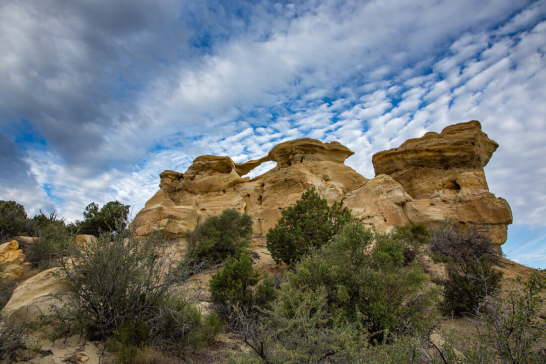 Blauer Himmel und Wolken über dem Graceful Arch in einer abgelegenen Wüste bei Aztec im Nordwesten von New Mexico
