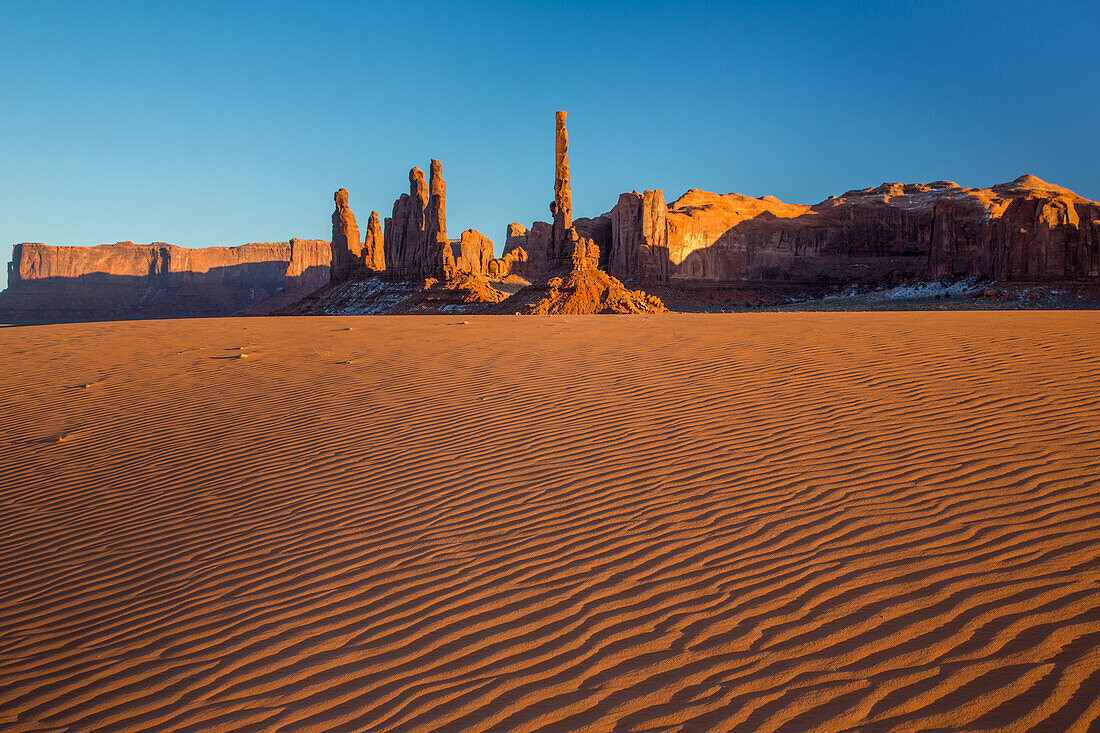 The Totem Pole & Yei Bi Chei with rippled sand dunes in the Monument Valley Navajo Tribal Park in Arizona.