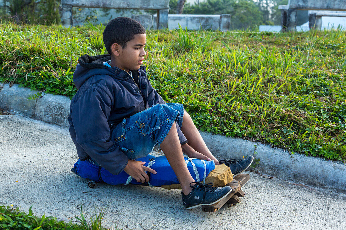 Ein dominikanischer Junge fährt auf seinem selbstgebauten Skateboard in der Nähe von Constanza in der Dominikanischen Republik