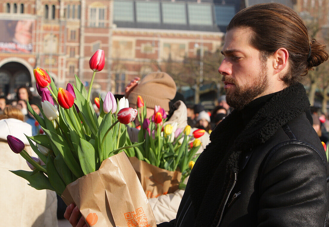 Ein Mann hält einen Tulpenstrauß, während Tausende von Menschen während des nationalen Tulpentages auf dem Museumsplatz in der Nähe des Rijskmuseums am 20. Januar 2024 in Amsterdam, Niederlande, kostenlos Tulpen pflücken. Heute ist der offizielle Beginn der Tulpensaison mit einem speziellen Tulpengarten, in dem die Menschen kostenlos Tulpen pflücken können. In diesem Jahr wird der 12. Jahrestag des von den niederländischen Tulpenzüchtern organisierten Pflückgartens besonders gefeiert. Der Amsterdamer Museumsplatz ist mit rund 200.000 Tulpen gefüllt. Diese Tulpen werden speziell zu einem riesig