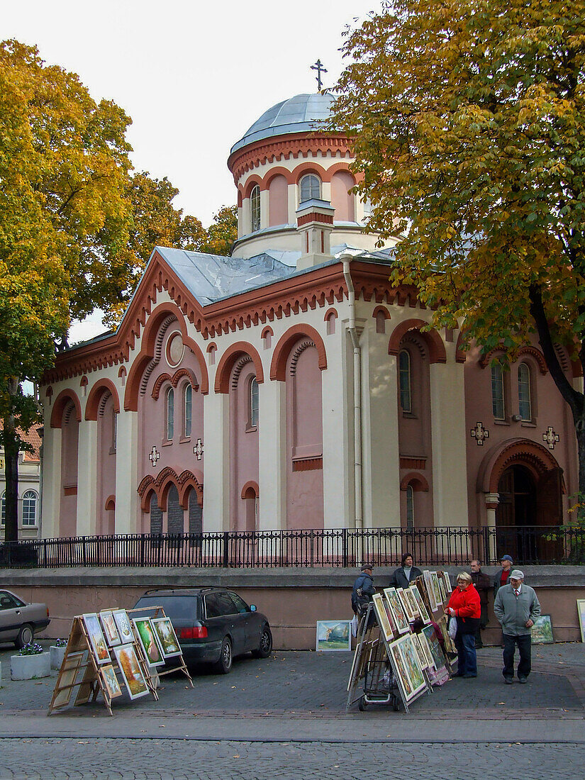 Menschen kaufen auf einem Straßenmarkt vor der Kirche St. Paraskeva in der Altstadt von Vilnius, Litauen, Kunst ein. Eine UNESCO-Welterbestätte. St. Paraskeva ist die älteste orthodoxe Kirche in Vilnius.