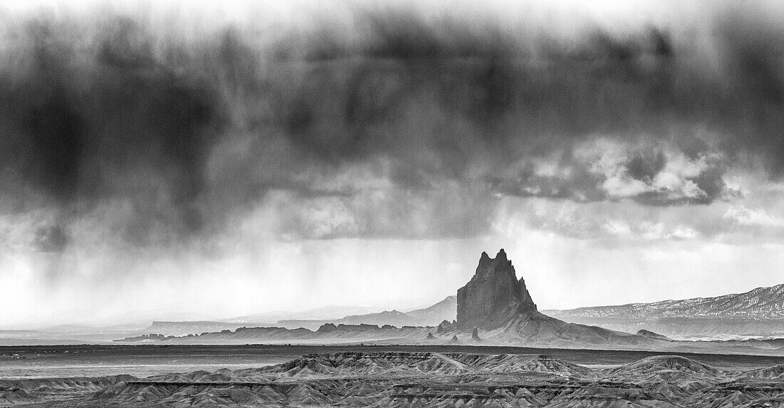 Shiprock ist ein vulkanischer Basaltmonolith im Navajo-Reservat in der Nähe der Stadt Shiprock, New Mexico. Virga ist der Name für diese Regenschlieren, die verdunsten, bevor sie den Wüstenboden erreichen